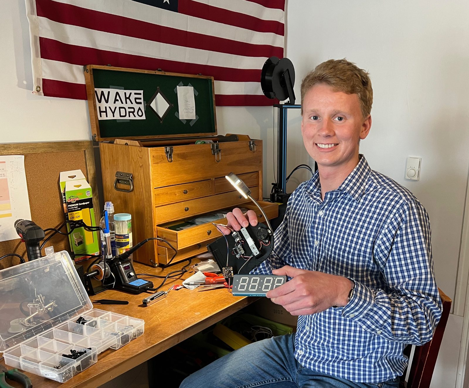 Jake Grim at his workbench in Gettysburg, holding a Wake Hydro circuit board